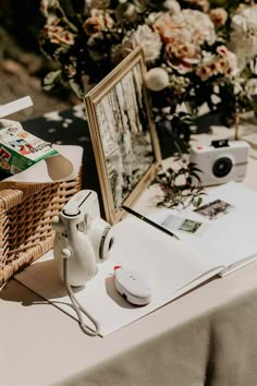 a table topped with flowers and pictures next to a basket filled with books on top of it