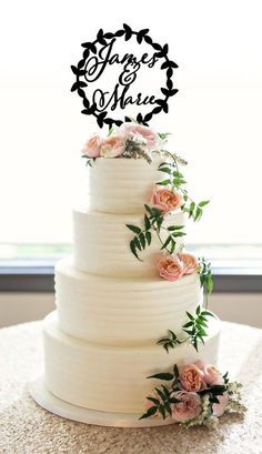 a white wedding cake with pink flowers on top and the words roses are made out of frosting