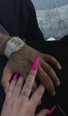 two hands with pink nail polish holding each other's fingers and wearing matching rings