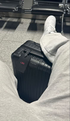 a person laying on the ground with their feet up next to a luggage bag in an airport