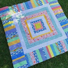 a patchwork quilt is laying on the grass