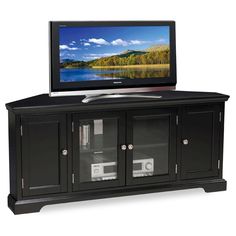 a flat screen tv sitting on top of a black entertainment center with doors and drawers