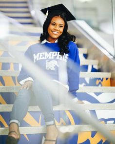 a woman sitting on some steps wearing a graduation cap and blue sweatshirt with the word mempflo printed on it