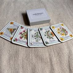 four playing cards sitting on top of a bed next to a box with the same design