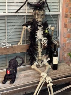 a skeleton sitting on a bench next to a bottle of wine and a black cat