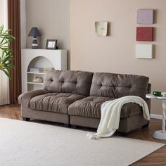 a living room with a brown couch and white rugs on the hardwood flooring