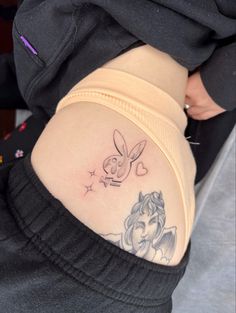 the back of a woman's stomach with a tattoo on her left side and an image of tinkerbell