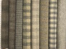 a row of different colored plaid fabric on a white wall in front of a window