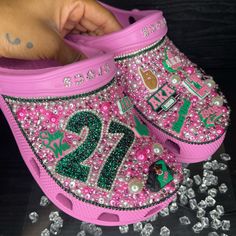 Elevate Your Style With These Personalized Aka Crocs, Adorned With Charms, Rhinestones, And Proudly Displaying Your Line Number. Celebrate Sisterhood In Every Step With This Unique Touch Of Elegance. Stride With Pride In These One-Of-A-Kind Crocs, A Perfect Blend Of Comfort, Style, And Individuality. For Alternative Sorority Options And To Customize Your Order, Please Email Or Dm Us Your Order Number, Line Number And Any Other Customizations. #Akastyle Email: Info@Artistrybynita.Com Ig: @Aartist Bedazzled Cow Print Crocs, Crocs With Rainbow Charms, Crocs Charms Chanel, Camo Bling Crocs, Alpha Kappa Alpha Sorority Wallpaper, Junk Crocs, Aka Crocs, Aka Decorations, Cheer Crocs