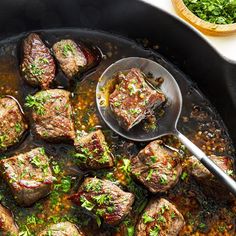 a skillet with meat and vegetables cooking in it