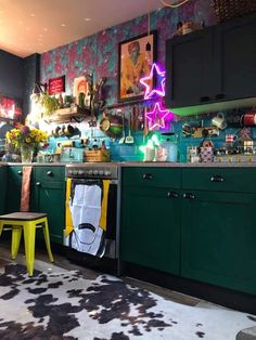 a kitchen with green cabinets and black counter tops, yellow stools, and a cow rug on the floor