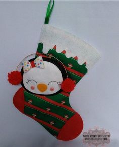 a small christmas stocking with a penguin on it's face and a green ribbon around the neck