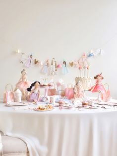 a table topped with lots of figurines next to a white chair and cake