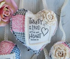 three heart shaped ornaments with words on them and flowers in the middle one is pink, white, and blue