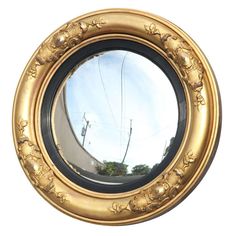 a round mirror reflecting the street and power lines in it's gold rimmed frame