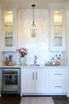 a kitchen with white cabinetry and wood flooring has a vase filled with flowers on the counter