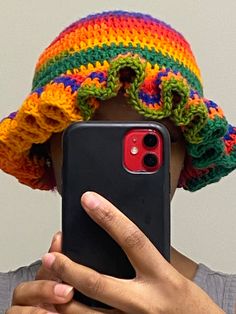 a person wearing a colorful hat holding a cell phone up to their face with one hand