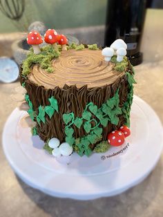 a cake that is on top of a plate with mushrooms and leaves around it in the shape of a tree stump