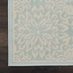 a white and blue rug on top of a wooden floor