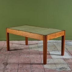 a wooden table sitting on top of a tiled floor next to a green wall and white tiles