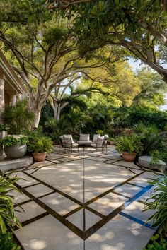 Four cushioned chairs around a small table on a geometric patio, surrounded by lush greenery and shaded by large trees. Concrete Pads Backyard, Large Concrete Patio Ideas, Modern Concrete Patio, Stamped Concrete Patio Ideas, Concrete Patio Ideas, Concrete Patio Makeover, Concrete Pad, Stamped Concrete Patio