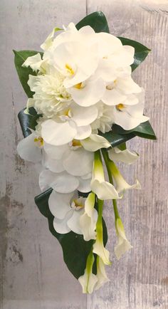 a bouquet of white flowers sitting on top of a wooden table next to a wall