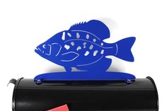 a blue fish on top of a black mailbox with a red tag attached to it