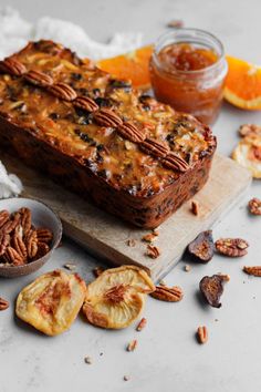 a loaf of bread with pecans and oranges around it