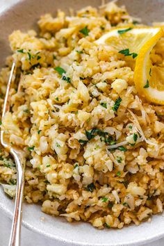 a white bowl filled with rice and lemon wedges