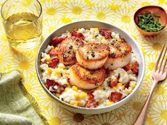 a bowl filled with rice and scallops next to a fork