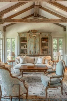 a living room filled with furniture and lots of windows covered in wood beams on the ceiling