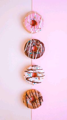 three donuts with sprinkles are hanging on a pink and white wall