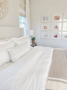 a bedroom with white bedding and pictures on the wall