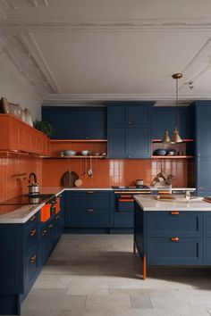 a kitchen with blue cabinets and orange accents