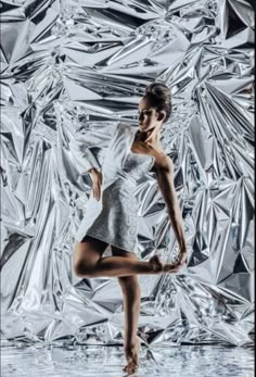 a woman is dancing in front of shiny foil