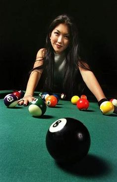 a woman leaning over a pool table with several billiards and balls in front of her