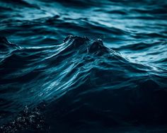 the water is very dark and blue in this photo, it looks like waves are coming up from the ocean