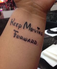 a wrist tattoo saying keep moving forward on someone's left arm in black ink