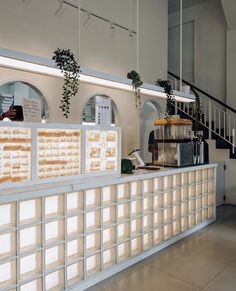 a counter with some food on it in a building next to stairs and plants hanging from the ceiling