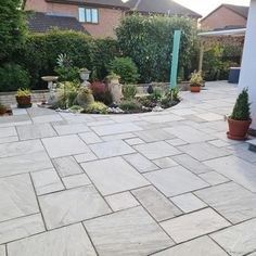 an outdoor patio area with potted plants and stone pavers flooring in front of the house