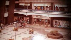 an old photo of people walking in front of a building with shops on the second floor