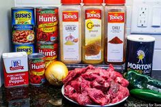 an assortment of spices and food items on a kitchen counter top, including tomatoes, onions, cornbreads, mustard, onion, garlic, seasonings, hot sauce, and more