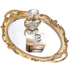 an ornate gold and clear mirror with a camera on it's side, in the shape of a heart