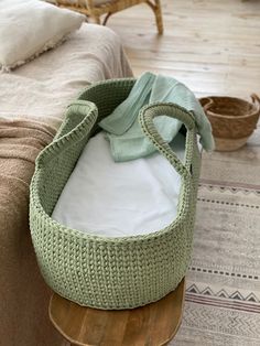 a baby crib sitting on top of a wooden table next to a basket filled with blankets