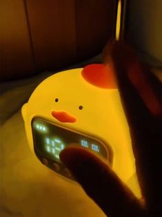 a person is holding up a clock that looks like a chicken with an alarm on it