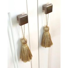 two gold tassels hang from the handles of white doors with square knobs