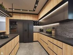 a modern kitchen with black counter tops and wooden cabinetry, along with an island in the middle