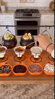 a wooden table topped with bowls filled with different types of desserts and toppings