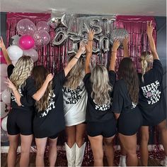 several women in black shirts and white shorts are holding up the number 50 balloons above their heads