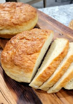 two loaves of bread sitting on top of a wooden cutting board